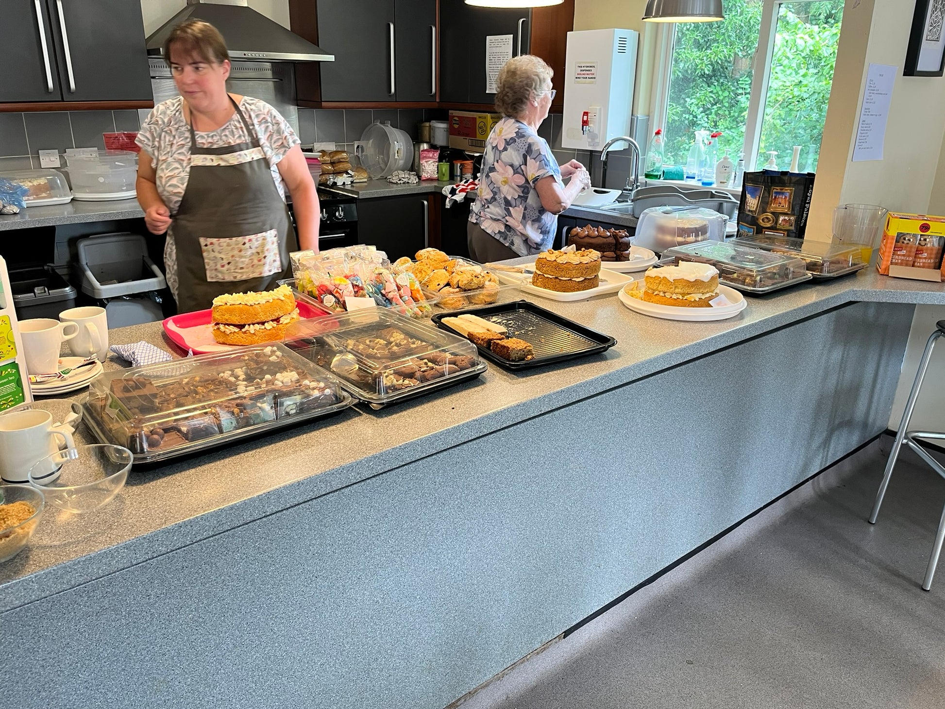 Two women in a kitchen with various baked goods on a counter